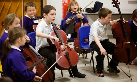 На уроке музыки мальчики играют на виолончелях.